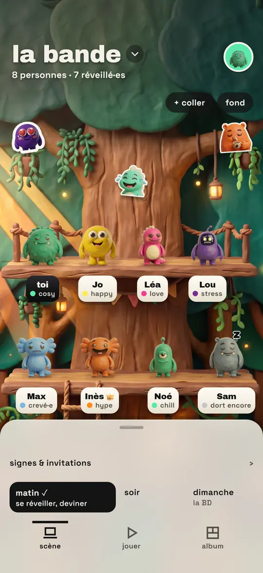 L’écran du groupe sur le mur de la cabane dans l’arbre : huit monstres en pâte sur deux étagères en bois, chacun avec son prénom et son mot d’humeur, un encore endormi en gris, une couronne à côté d’un prénom, trois emotes en pâte collées au mur.
